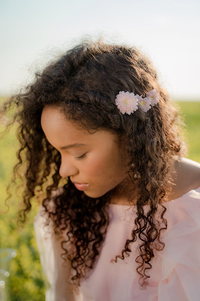 Portrait of a woman with curly hair and floral accessory, enjoying a peaceful moment outdoors.